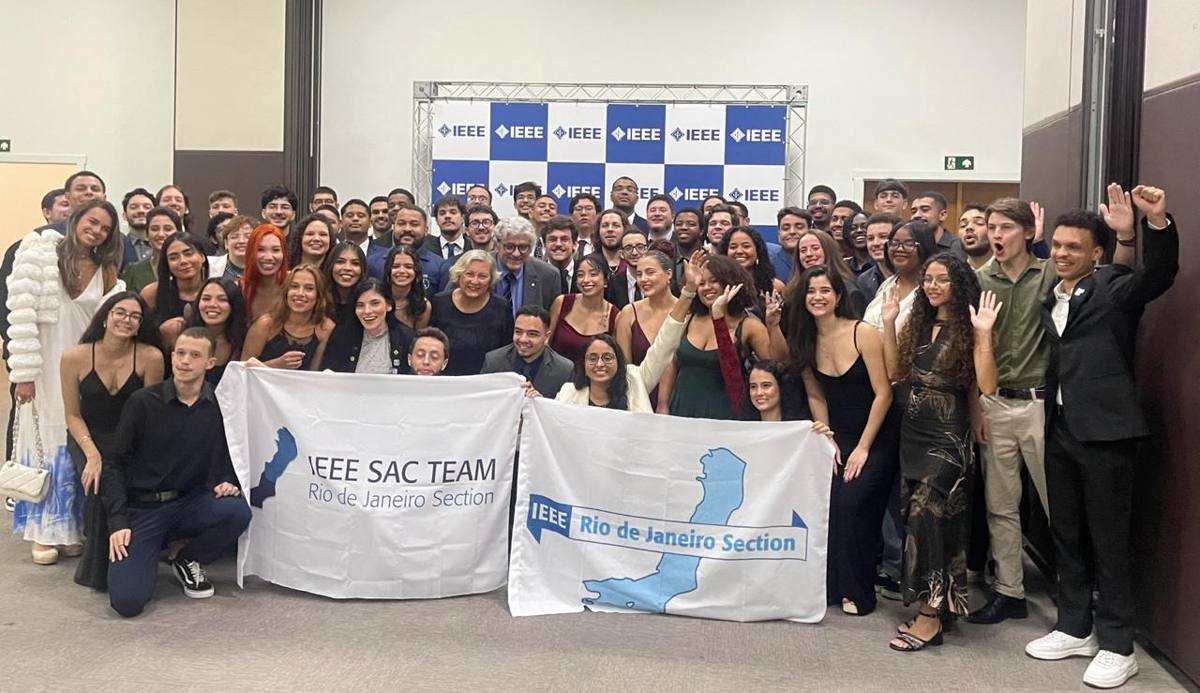 Grupo de voluntários e membros com as bandeiras do IEEE SAC Team Rio e da Seção Rio de Janeiro